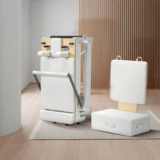 Compact, foldable Pilates reformer with white upholstery and modern minimalist design.