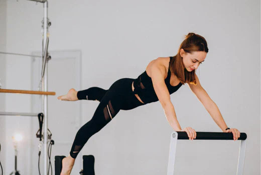 a woman performing a challenging exercise on a Pilates reformer machine